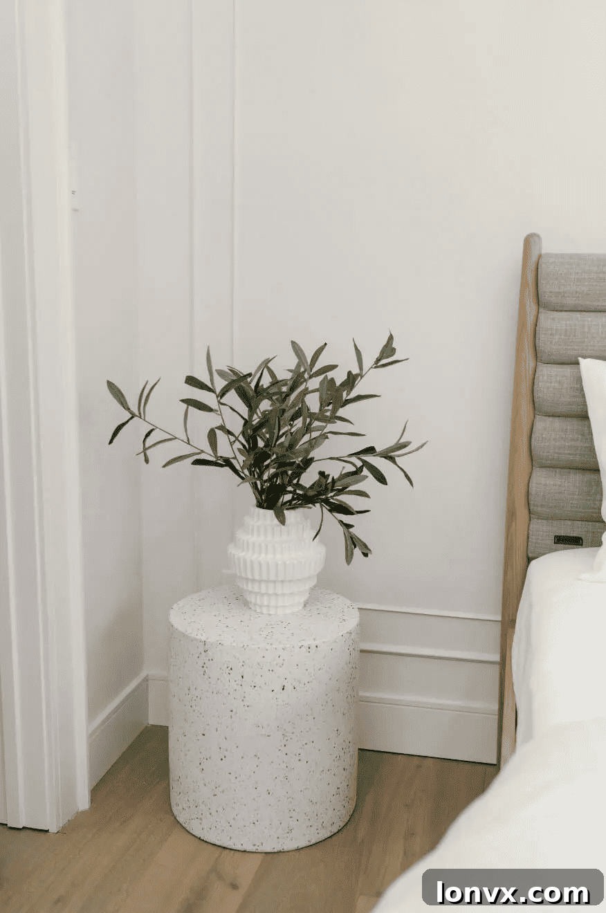 A modern, minimalist space featuring a curved, cream-colored sofa and a round wooden coffee table.